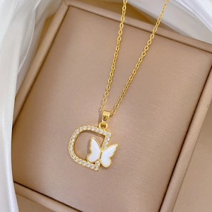Macro detail of gold D-pendant necklace with white butterfly and crystals in box