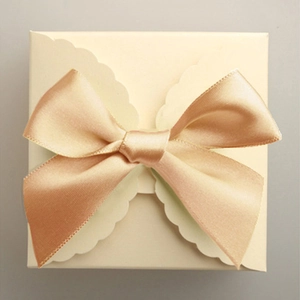 Cream square gift box with wavy edges and large champagne gold satin ribbon bow