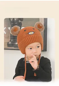Détail du bonnet tricoté marron pour bébé avec oreilles d'ours, broderie cœur et liens
