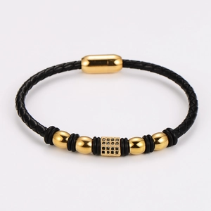 Detail of black braided leather bracelet with gold magnetic clasp and inset stones