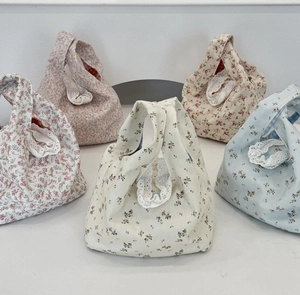 Close-up of floral canvas wristlet bags featuring delicate white lace trim and pastel colors