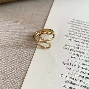 Detailed view of a gold-plated stainless steel wavy open ring on vintage paper background