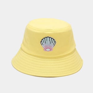 Detailed close-up of shell embroidery on a bright yellow cotton bucket hat crown