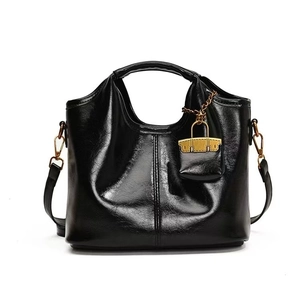 Close-up of black oil wax leather tote bag with gold hardware lock and glossy texture