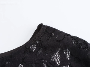 Close-up of elegant black floral lace neckline and sheer fabric detail on this dress
