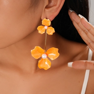 Detail of bohemian orange flower drop earrings with pearls on a professional model