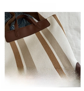 Macro view of striped canvas tote featuring leather handles and reinforced corner details