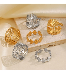Detailed view of adjustable leaf rings in gold and silver finishes on a stone base