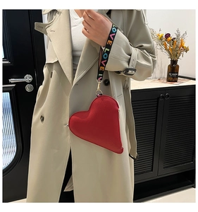 Close-up of red heart-shaped handbag featuring a wide strap with LOVE letter prints