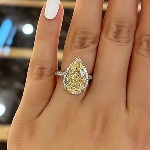 Macro view of pear-cut yellow gemstone ring with halo diamonds and a sparkling band