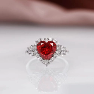 Macro shot of silver ring featuring a red heart-shaped gemstone with white diamond halo