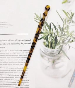 Detail view of a tortoise shell acetate hair stick resting on a minimalist magazine page