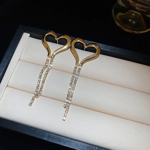 Detail of heart fringe earrings with gold plating and sparkling white rhinestones