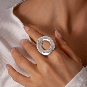 Close-up of minimalist silver hollow circular ring worn on finger with metallic texture