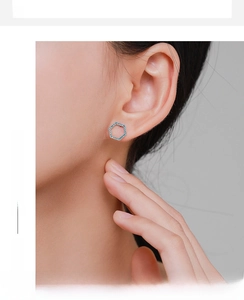 Detail of S925 sterling silver hexagonal stud earring with blue stone pavé on female ear