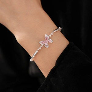 Détail d'un bracelet papillon en zircon rose avec chaîne en argent au poignet