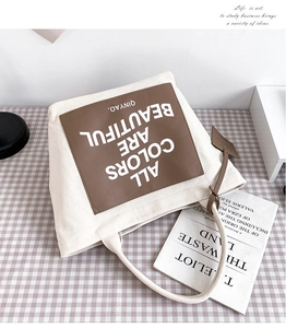 Close-up of canvas tote bag with brown leather patch and printed artistic lettering