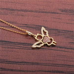 Detail of gold angel wing pendant with a red heart crystal on a brown texture
