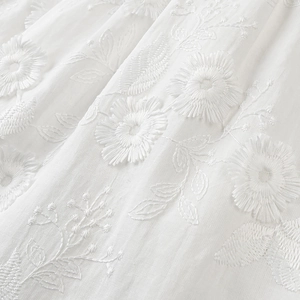 Detailed macro view of white floral embroidery on a premium summer cotton fabric set