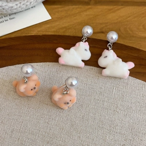 Close-up of cute flocked animal earrings with unicorn and bear designs and white pearls