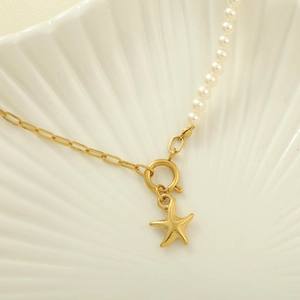 Detailed close-up of a starfish pendant on a gold chain with pearls on a shell base