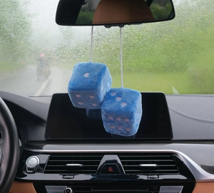 Blue plush heart dice car pendant hanging from a rearview mirror in close-up detail