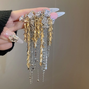 Detail of silver needle chain tassel earrings with floral motifs and sparkling rhinestones