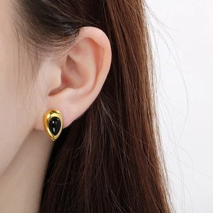 Vue détaillée d'une boucle d'oreille goutte en or avec une pierre centrale en opale noire
