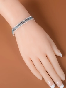 Detailed view of silver-tone bracelet with blue and white stones on female wrist