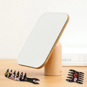Close-up of resin afro hair picks and a minimalist cork mirror on a solid wood base