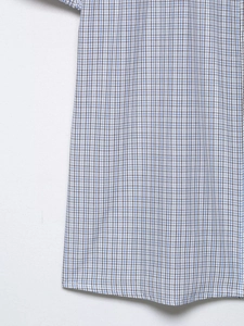 Close-up of blue and brown plaid stretch poplin fabric showing the hem and stitching detail