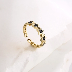 Detailed close-up of gold star ring with black enamel inlay and adjustable open band