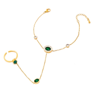 Elegant gold hand chain featuring green oval gemstones and a matching butterfly ring design