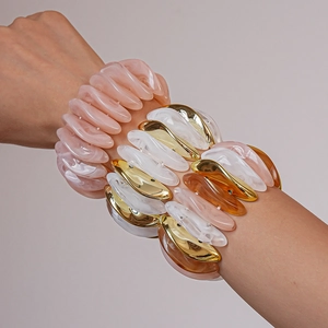 Close-up of stacked acrylic resin bracelets with marble texture and gold metal accents