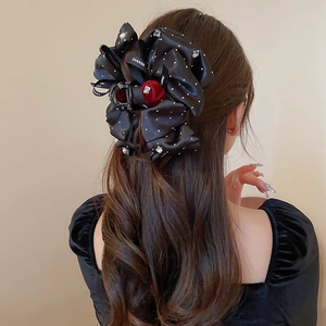 Detail showing a black satin bow hair claw with rhinestones and CHANGE ribbon on hair