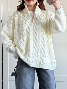 Detail of white cable knit sweater with high neck zipper and textured knit fabric pattern