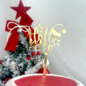 Dettaglio del topper per torta Ho Ho Ho in acrilico dorato su una torta di Natale rossa
