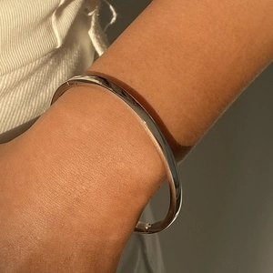 Nahaufnahme eines polierten silbernen Edelstahl-Armreifs mit Schnallenverschluss am Handgelenk
