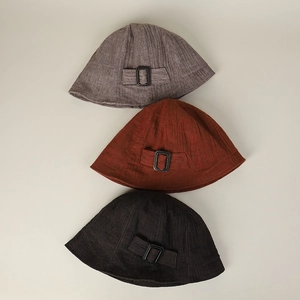 Flat lay of linen bucket hats in grey, red, and brown with textured fabric and buckles