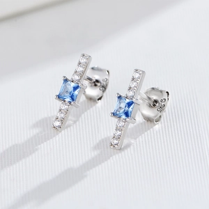 Macro detail of geometric 925 silver stud earrings with blue square zircon and crystals