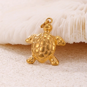 Polished 18k gold plated stainless steel sea turtle pendant on natural coral background
