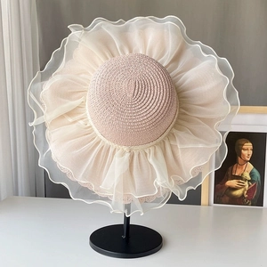 Close-up of elegant beige wide-brim straw hat with tiered white organza lace edges