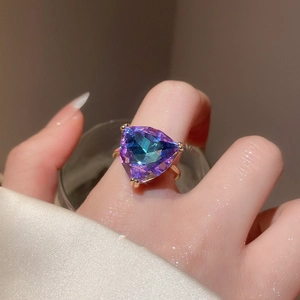 Detail of a large triangle-cut rainbow gemstone ring set in minimalist gold prongs