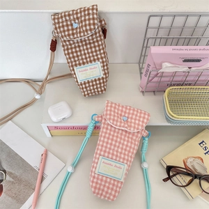 Close-up of quilted plaid camera storage bags in brown and pink with adjustable straps