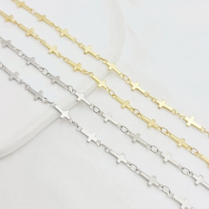 Golden and silver stainless steel cross chains displayed on marble surface