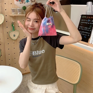 Corduroy drawstring storage bag in pink tie-dye with brand tag held by model