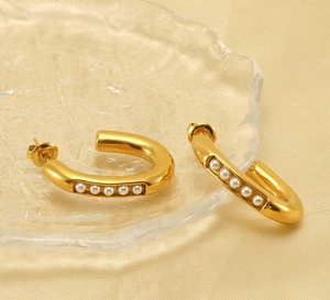 Detailed close-up of gold-plated U-shaped earrings with five pearls on silk
