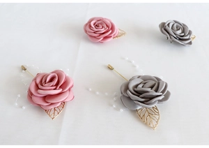 Détail de corsages de roses en satin avec feuilles dorées et épingles de revers