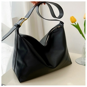 Detail view of large black tote bag side with fine leather texture and golden buckle