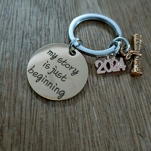 Close-up of golden graduation keychain with My Story Is Just Beginning and 2024 charms